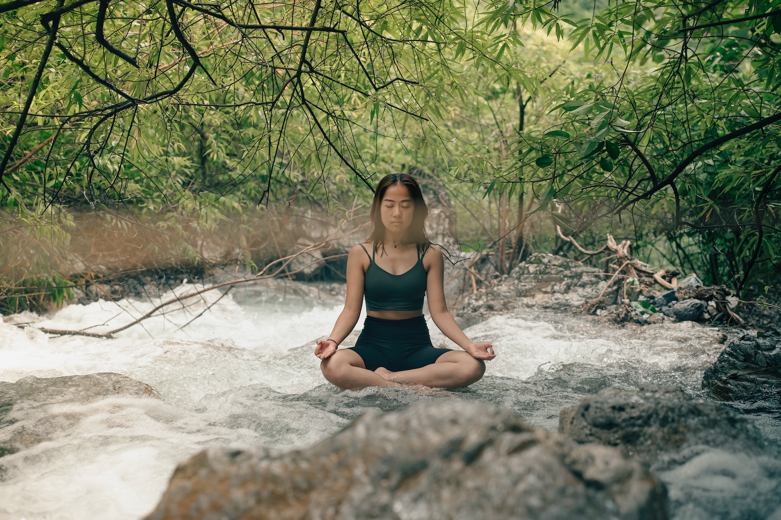 a woman sitting in a river meditating