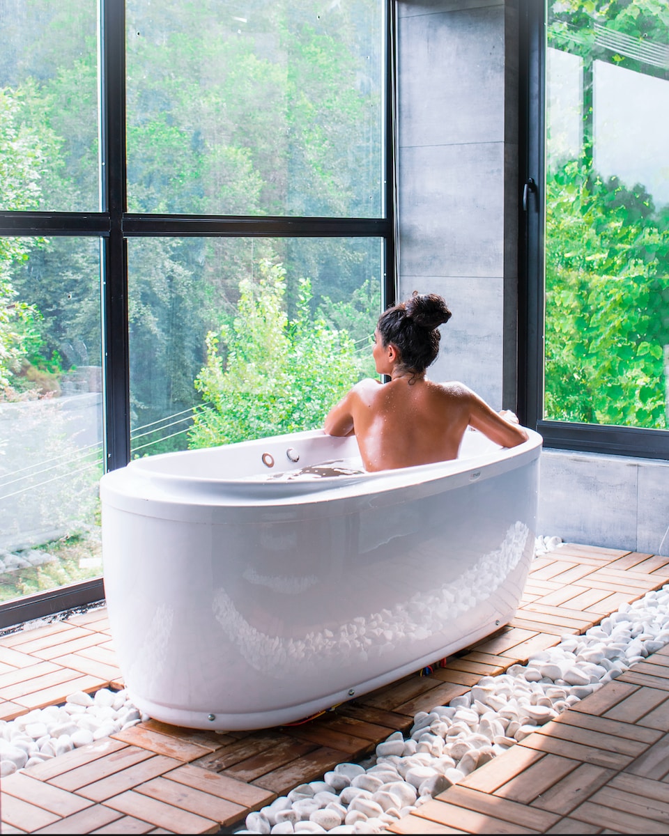 a woman sitting in a bathtub in front of a window